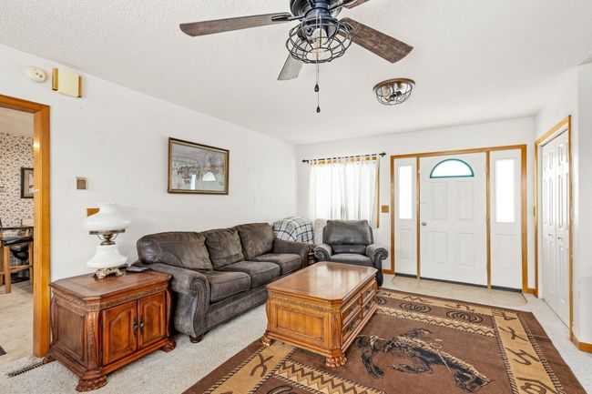 Living area with light carpet, a textured ceiling, and a ceiling fan | Image 38