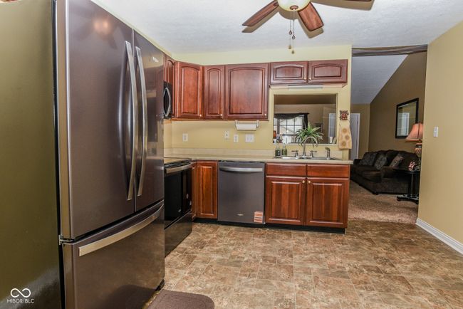 kitchen with appliances, a sink, light countertops, a ceiling fan | Image 5