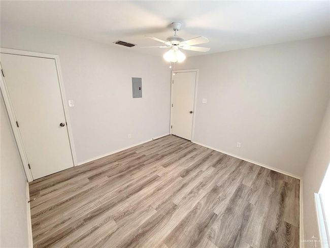Unfurnished bedroom featuring electric panel, light wood finished floors, and ceiling fan | Image 17