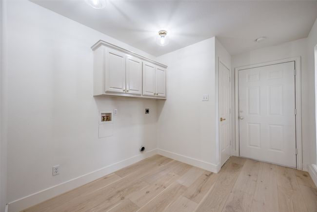 Laundry area featuring hookup for an electric dryer, light wood finished floors, hookup for a washing machine, and cabinet space | Image 32