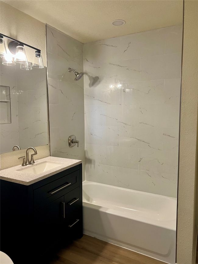 Bathroom featuring wood finished floors, vanity, shower / washtub combination, and a textured ceiling | Image 26