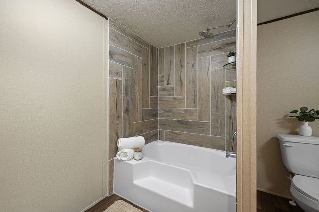 Bathroom featuring wooden walls, toilet, walk in shower, a textured ceiling, and a tub | Image 26