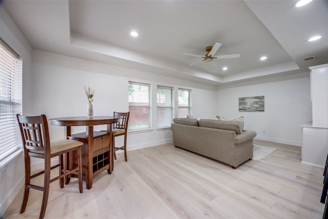 Living room featuring a raised ceiling, a ceiling fan, light wood-style flooring, and recessed lighting | Image 13