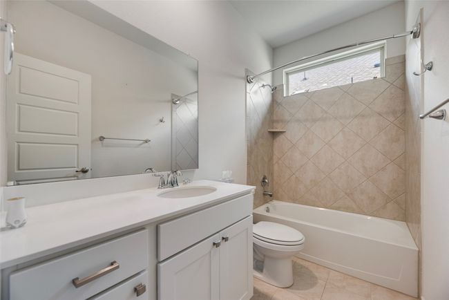 Bathroom with toilet, tub / shower combination, vanity, and tile patterned flooring | Image 28