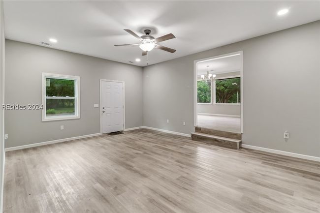 Empty room with ceiling fan with notable chandelier and light wood-type flooring | Image 21