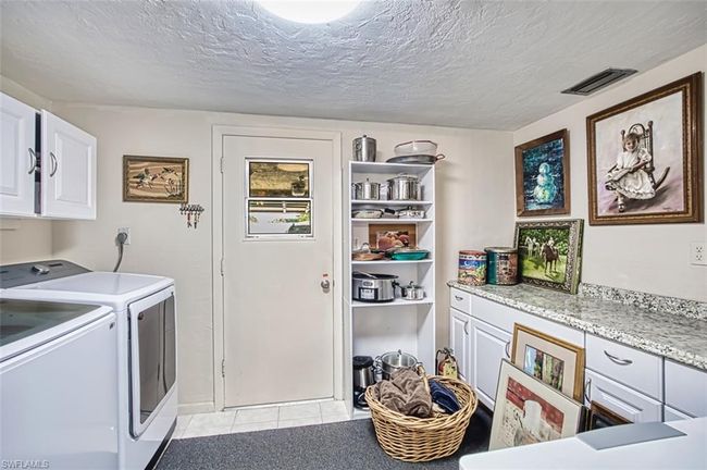 Laundry room with cabinet space, washer and dryer, light tile patterned floors, and a textured ceiling | Image 30