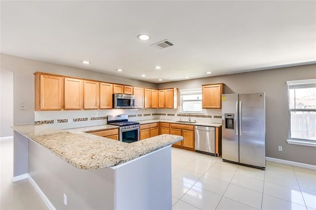 Kitchen with stainless steel appliances, tasteful backsplash, a peninsula, light stone counters, and recessed lighting | Image 12