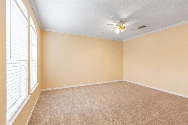 Carpeted spare room featuring a wealth of natural light, a ceiling fan, a textured ceiling, and visible vents | Image 21