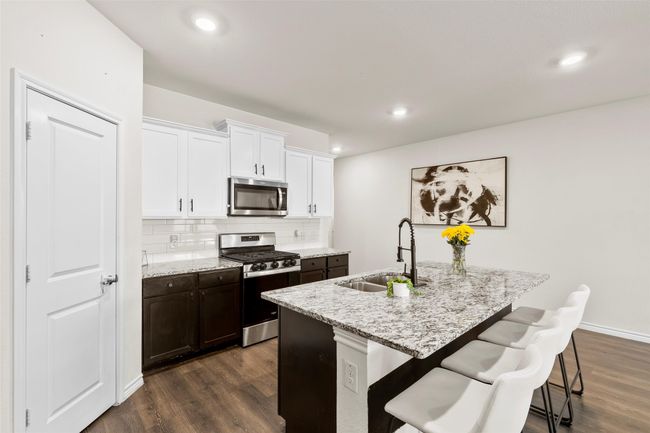 Kitchen with dark wood-type flooring, a breakfast bar area, stainless steel appliances, and a sink | Image 10