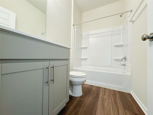 Bathroom featuring vanity, wood finished floors, toilet, and washtub / shower combination | Image 9