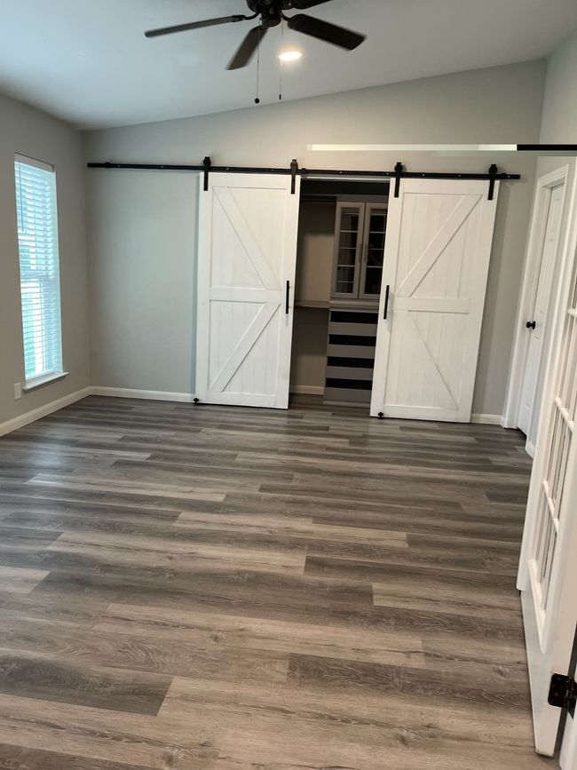 Unfurnished bedroom with dark hardwood / wood-style floors, vaulted ceiling, and a barn door | Image 16