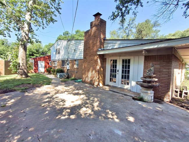 Back of house featuring french doors, a chimney, brick siding, and a patio | Image 30