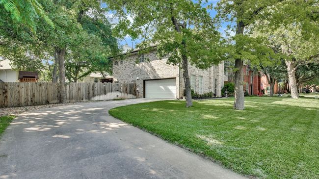 View of front of home with driveway, brick siding, an attached garage, and a chimney | Image 25