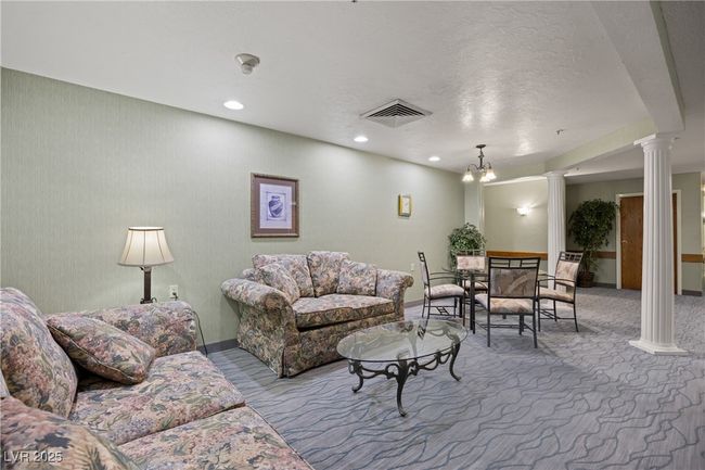 Carpeted Common living room with a textured ceiling, visible vents, baseboards, recessed lighting, and ornate columns | Image 38