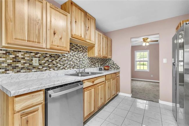 Kitchen featuring light brown cabinetry, a sink, tasteful backsplash, light countertops, and appliances with stainless steel finishes | Image 24