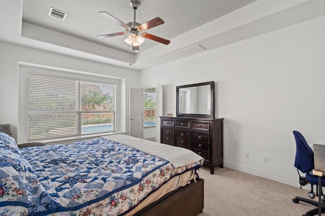 Bedroom featuring a tray ceiling, light carpet, baseboards, and a ceiling fan | Image 13