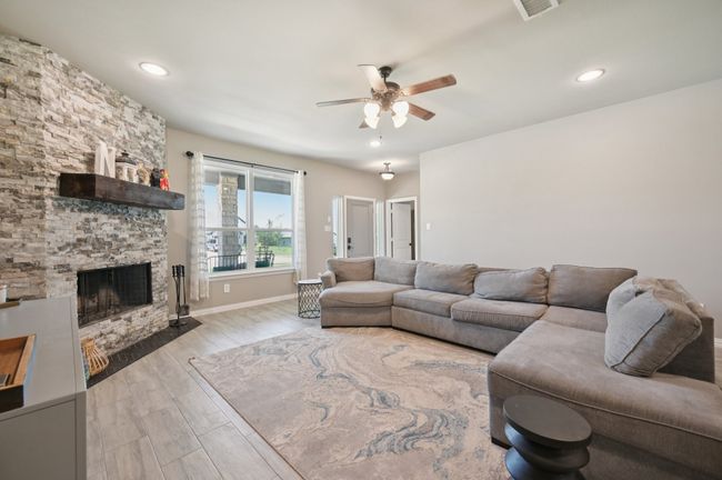 Living room with ceiling fan, wood finished floors, a stone fireplace, and recessed lighting | Image 4