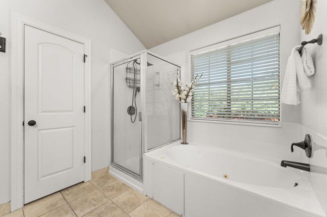 Bathroom with a shower stall, a bath, lofted ceiling, and tile patterned floors | Image 17