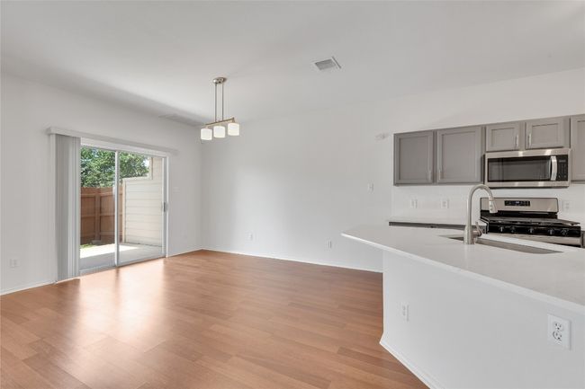Kitchen with appliances with stainless steel finishes, gray cabinets, light wood finished floors, light countertops, and pendant lighting | Image 6