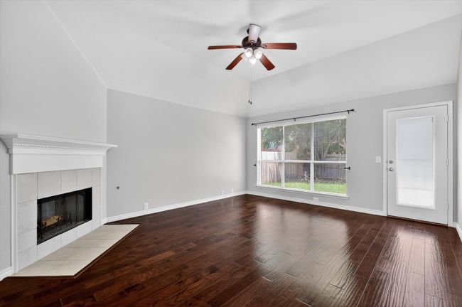 Living room featuring ceiling fan, wood finished floors, vaulted ceiling, and a tile fireplace | Image 9