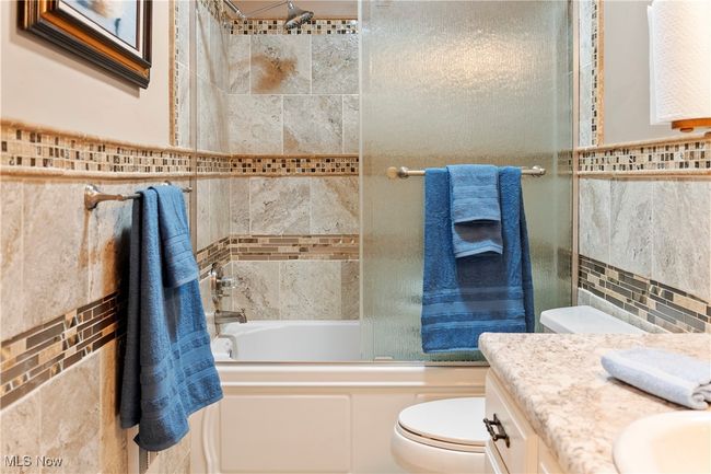 Bathroom featuring shower / bath combination with glass door, tile walls, toilet, and​​‌​​​​‌​​‌‌​‌‌​​​‌‌​​‌‌​‌​​​​​‌ vanity | Image 16