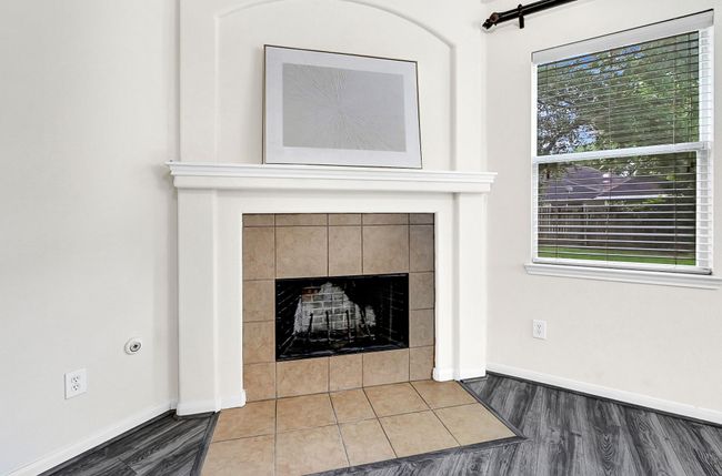 The cozy corner fireplace with tile surround and niche above is the perfect feature for this bright living room. | Image 15
