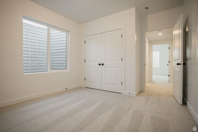 Unfurnished bedroom with light colored carpet, multiple windows, and baseboards | Image 41