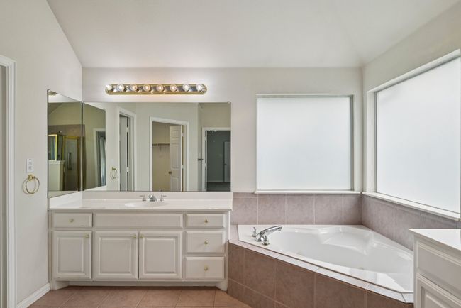 Bathroom with a stall shower, vanity, a bath, and light tile patterned floors | Image 12