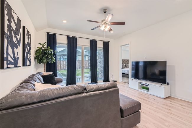 Living area featuring ceiling fan, lofted ceiling, baseboards, and light wood-style flooring | Image 6
