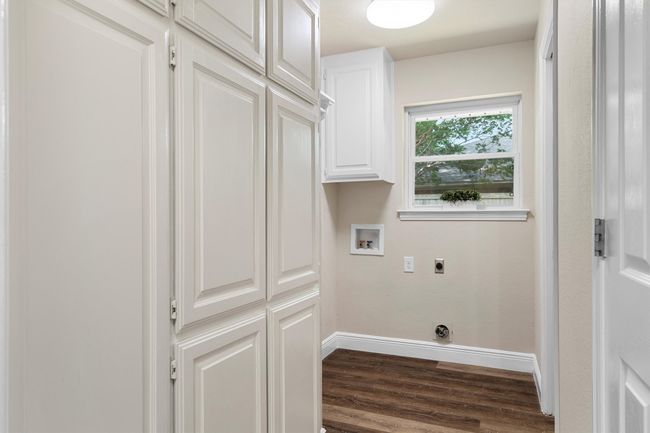 The laundry room has lots of built in storage and a window. | Image 17