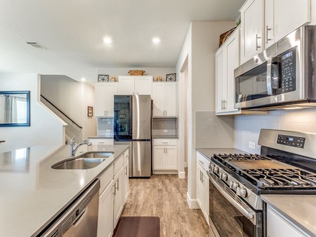 Kitchen featuring stainless steel appliances, light wood-type flooring, white cabinets, tasteful backsplash, and recessed lighting | Image 14