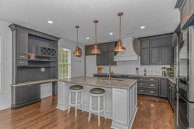 Kitchen featuring custom exhaust hood, open shelves, a sink, light stone counters, and dark wood-type flooring | Image 10