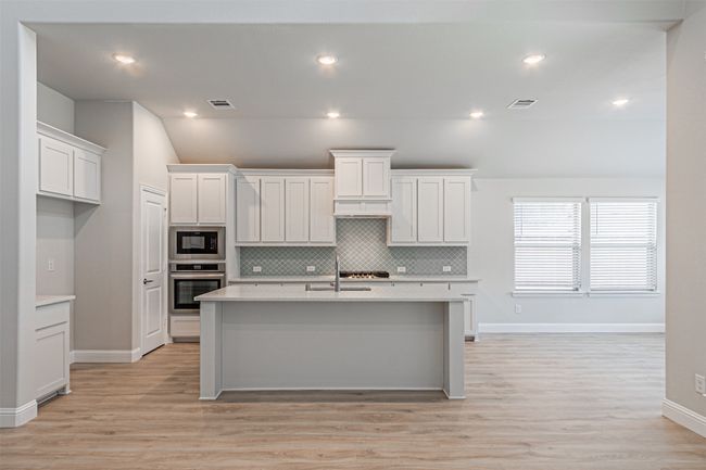 Kitchen featuring oven, built in microwave, light countertops, decorative backsplash, and vaulted ceiling | Image 14