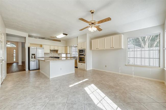Kitchen is open to breakfast nook with a gas fire place. | Image 7