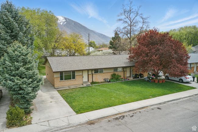 Ranch-style house with concrete driveway, a front lawn, a mountain view, brick siding, and roof with shingles | Image 33