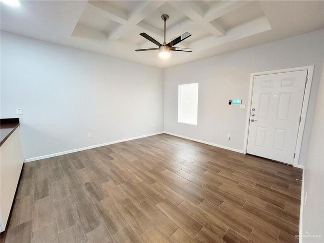 Unfurnished room featuring baseboards, ceiling fan, beamed ceiling, wood finished floors, and coffered ceiling | Image 17