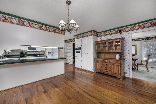 Kitchen with white appliances, a textured ceiling, white cabinetry, dark hardwood / wood-style flooring, and sink | Image 14