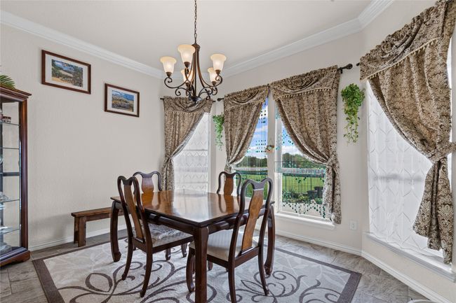 Dining room with ornamental molding, plenty of natural light, a chandelier, and baseboards | Image 9