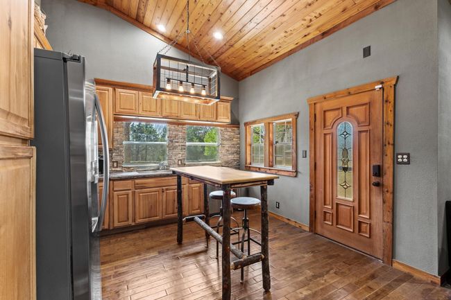 Kitchen with high vaulted ceiling, dark wood-type flooring, decorative backsplash, wood ceiling, and freestanding refrigerator | Image 22