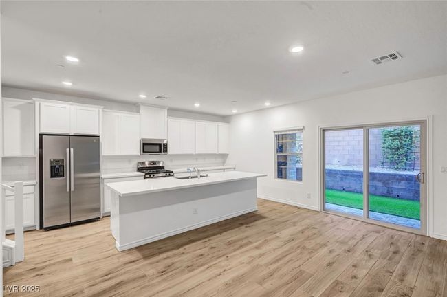 Kitchen with a sink, appliances with stainless steel finishes, visible vents, light wood-style floors, and light countertops | Image 9