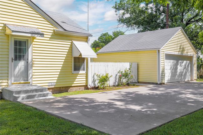 View of side of property featuring an outbuilding, roof with shingles, and a garage | Image 40
