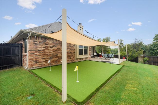 Back of property with an area to practice putting, a patio area, brick siding, and a chimney | Image 20