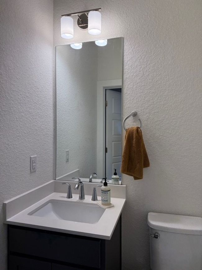 Half bathroom featuring toilet, vanity, and a textured wall | Image 8