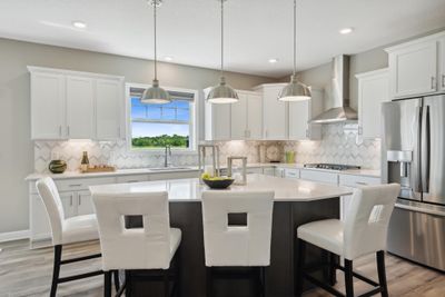 (Photo of a decorated model, actual homes finishes will vary) The Washburn offers a gourmet kitchen with Frigidaire professional appliances, quartz countertops, soft close cabinets, under cabinet lighting and walk in pantry. | Image 2