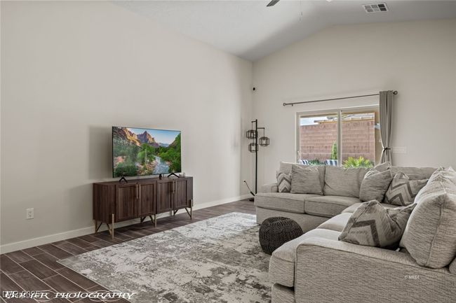 Living area featuring ceiling fan, dark wood-style floors, baseboards, and high vaulted ceiling | Image 20