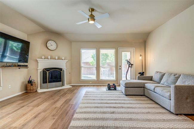 Living area with a ceiling fan, a fireplace with raised hearth, wood finished floors, and vaulted ceiling | Image 20