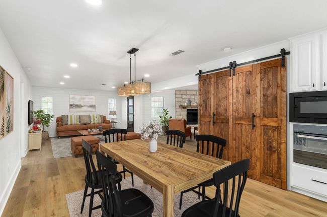 Cozy dining area with rustic charm, featuring bi-fold barn doors, seamlessly connected to a spacious living room. Perfect for entertaining! | Image 15