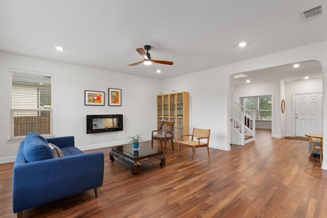Living area with arched walkways, wood finished floors, ceiling fan, stairway, and recessed lighting | Image 7