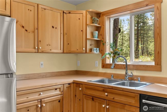 Deep stainless sink perfectly positioned beneath a bright window. Open shelving and spacious counters offer functionality and rustic charm | Image 25