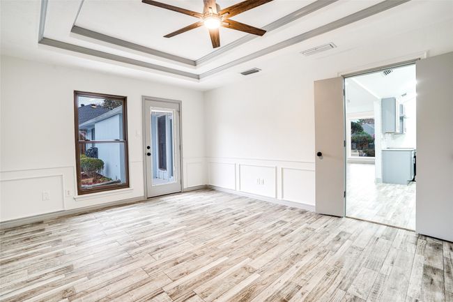 Unfurnished room with light wood-style floors, ceiling fan, a tray ceiling, wainscoting, and a decorative wall | Image 10
